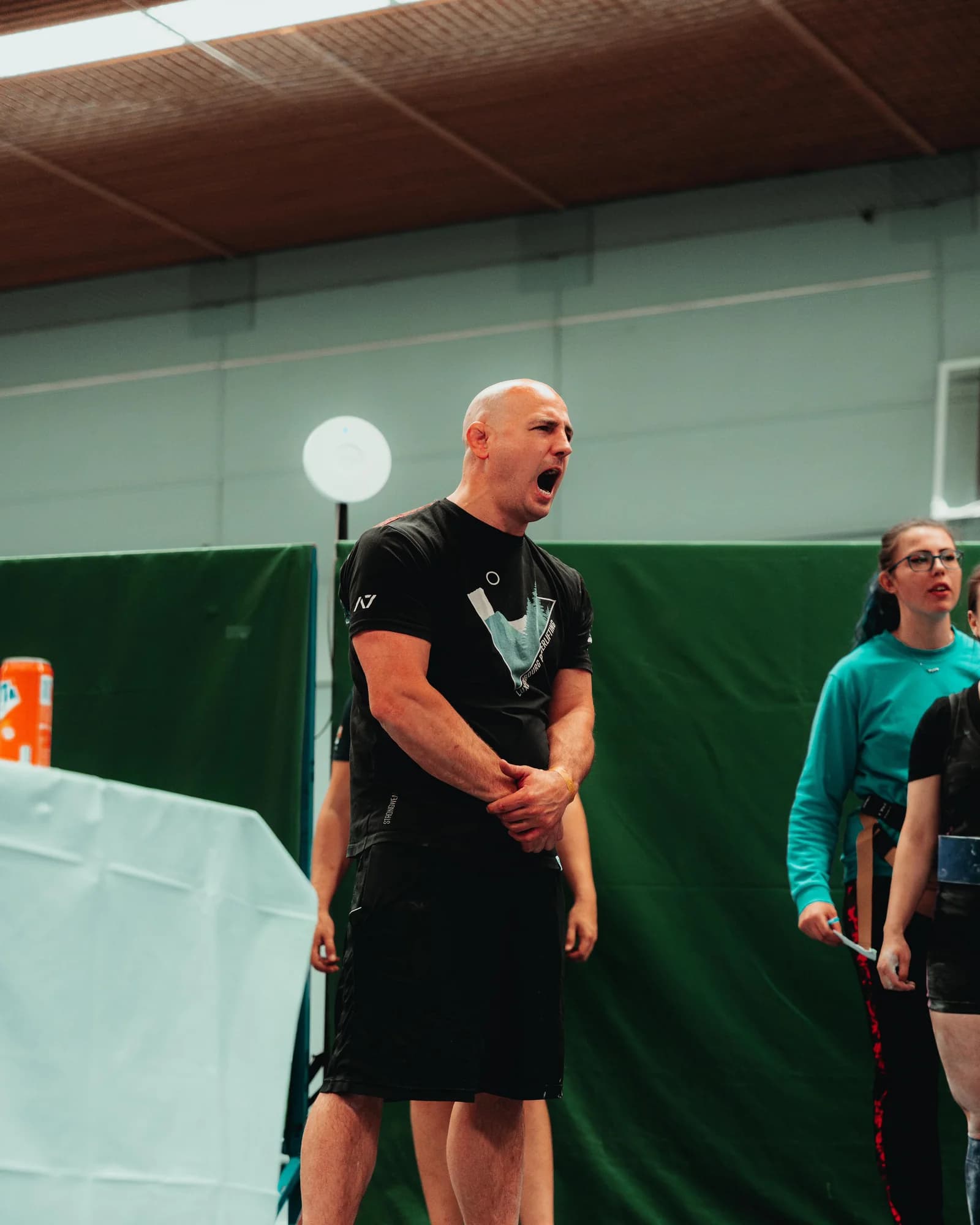 Bram Strik coacht een atleet langs het powerliftingplatform
